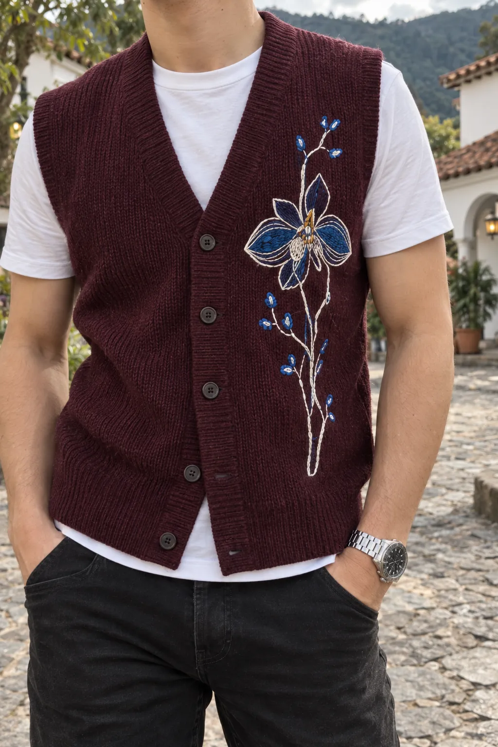 Detalle de la orquídea bordada en azul y blanco sobre el chaleco de punto vinotinto.