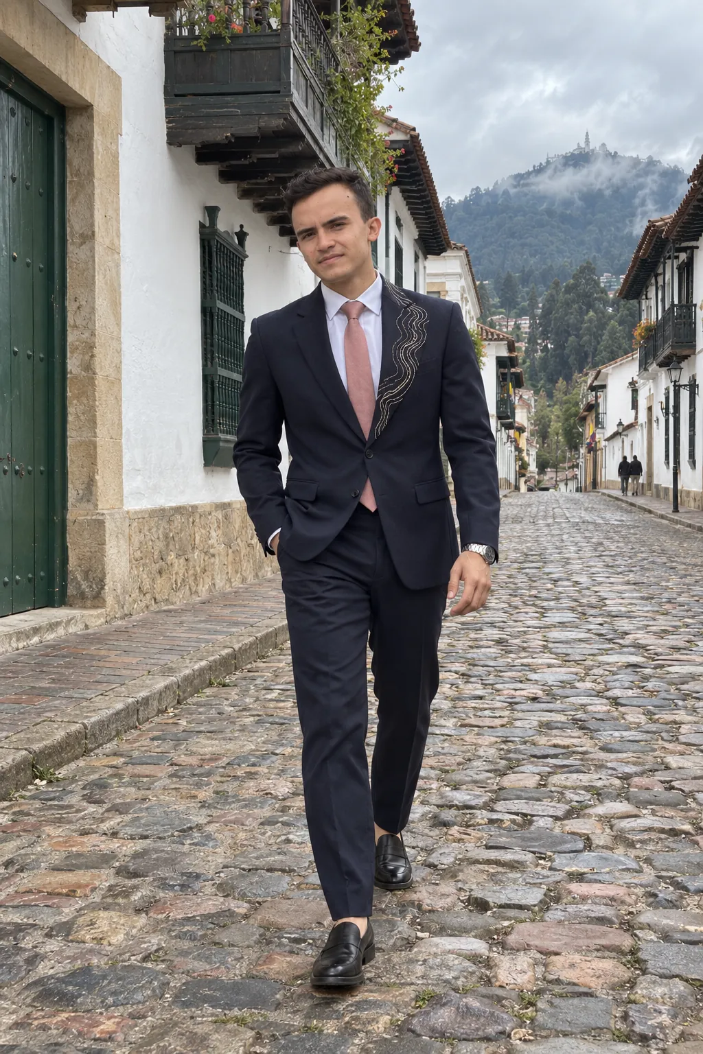 Days camina por una calle empedrada de La Candelaria, en Bogotá, con el traje azul marino y una mano en el bolsillo. Toma de campaña.