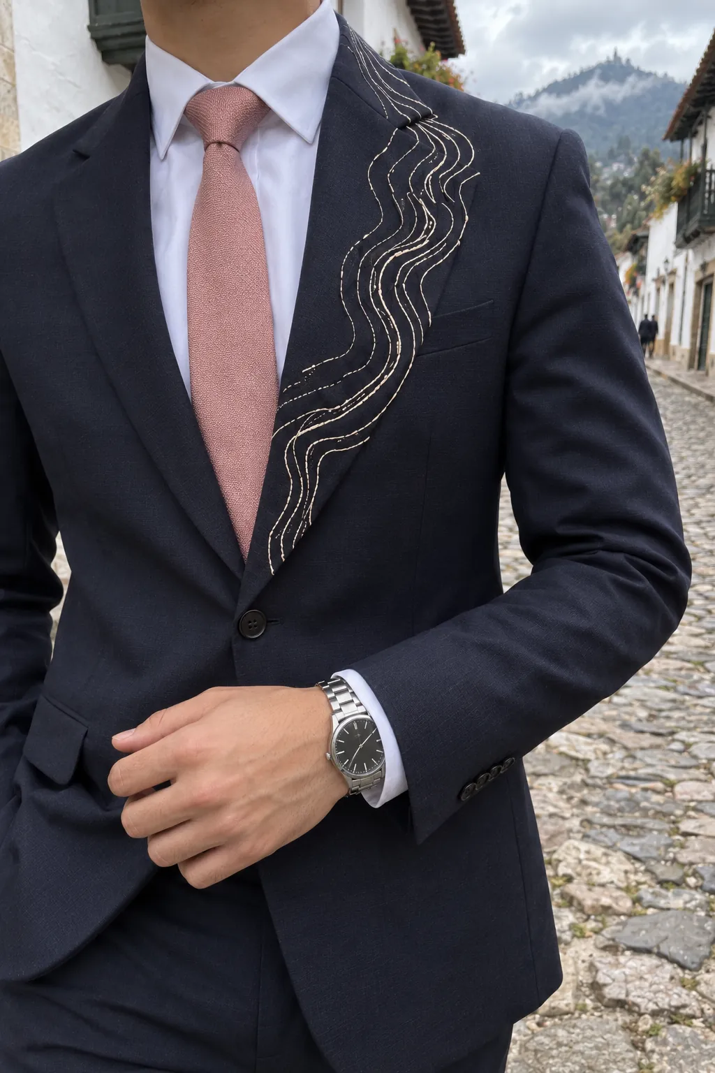 Detalle de las curvas de nivel bordadas en marfil sobre la solapa izquierda del traje azul marino.