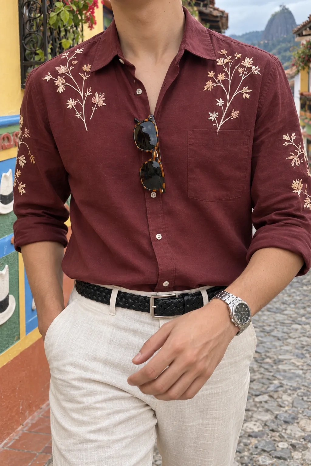 Detalle de las flores bordadas en marfil sobre el pecho y las mangas de la camisa vinotinto.