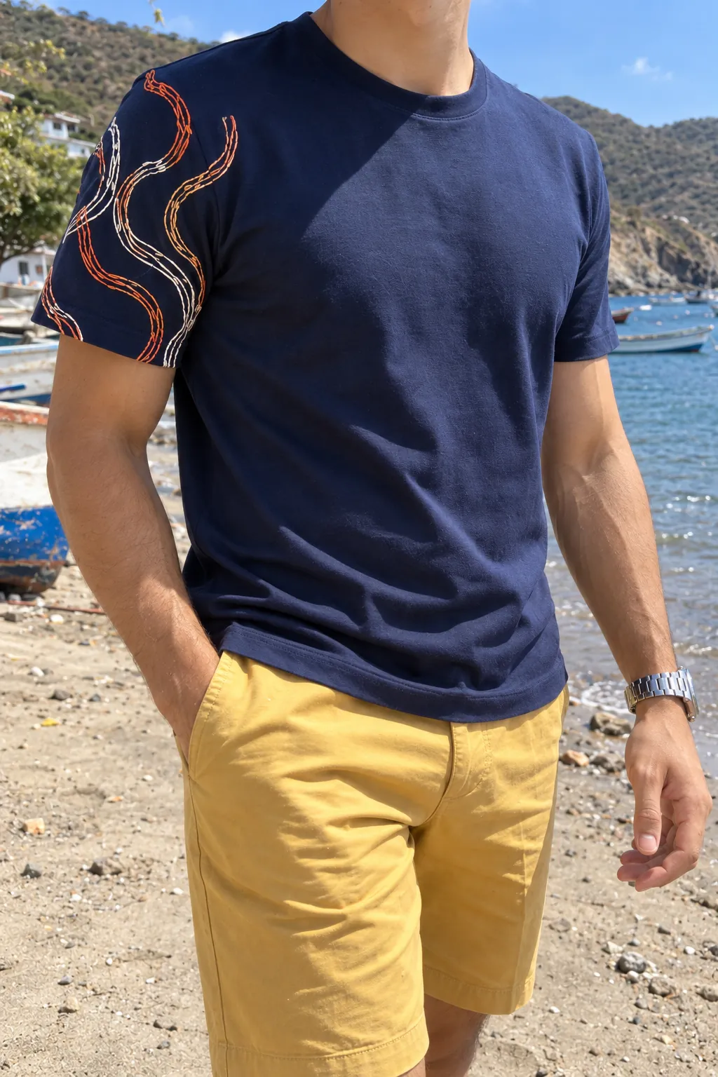 Detalle de las olas bordadas en cobre y marfil sobre la manga de la camiseta azul marino.